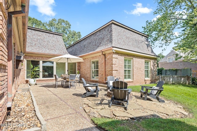 back of property featuring a lawn, a patio, and a fire pit