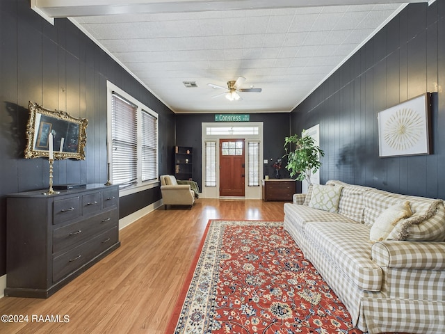 living room with ceiling fan, ornamental molding, wooden walls, and light hardwood / wood-style floors