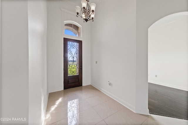 entrance foyer featuring light tile patterned flooring, crown molding, a chandelier, and a high ceiling