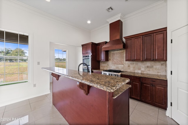 kitchen with custom range hood, a breakfast bar area, light tile patterned floors, and an island with sink