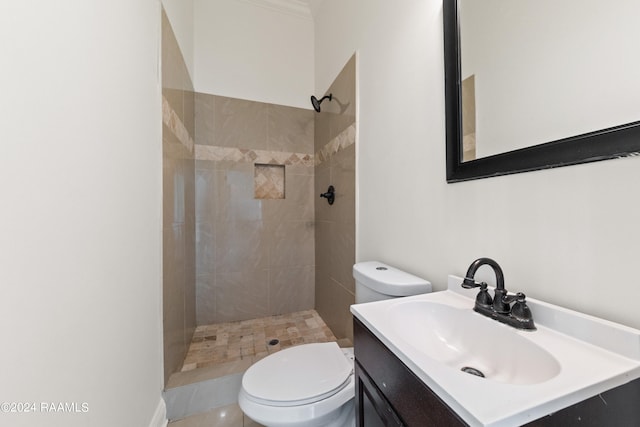 bathroom with a tile shower, vanity, and toilet