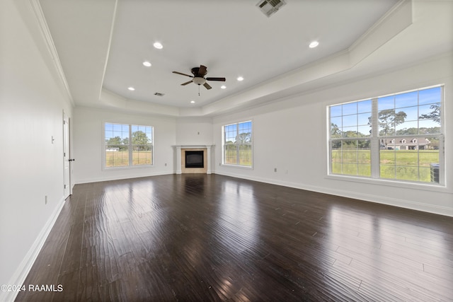 unfurnished living room with ornamental molding, a tray ceiling, ceiling fan, and dark hardwood / wood-style flooring