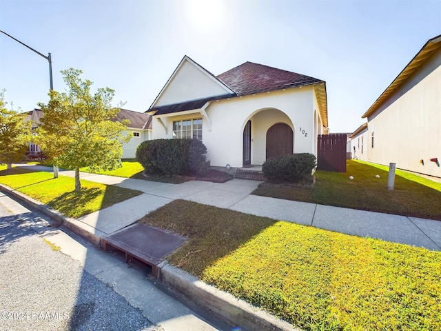 102 Rue Gambetta, Lafayette, LA 70507 - view of front of home featuring stucco siding, a front lawn, and a shingled roof