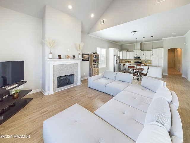 living room featuring a fireplace, high vaulted ceiling, light hardwood / wood-style flooring, and crown molding