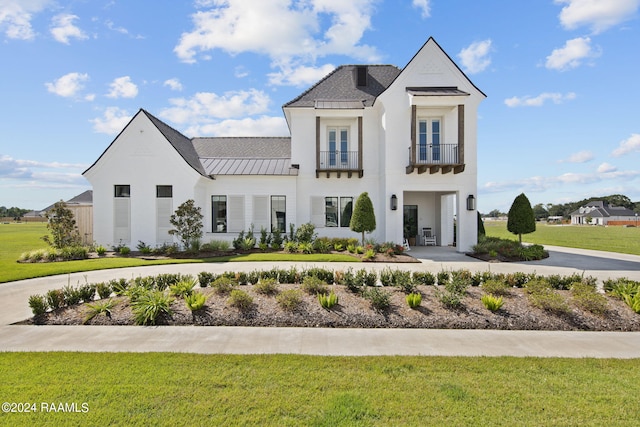 view of front of house featuring a balcony and a front lawn