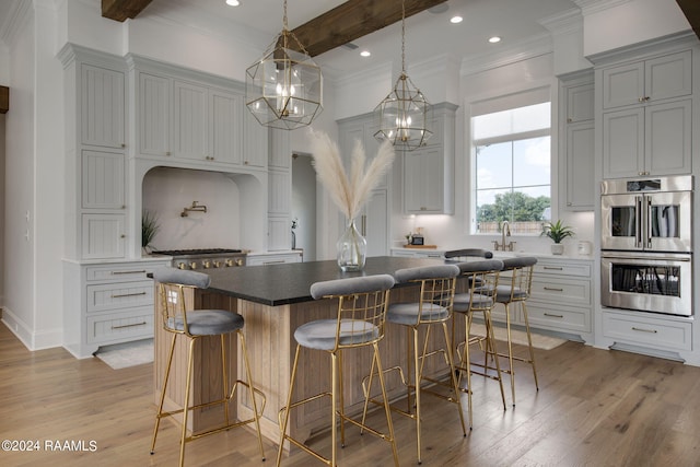 kitchen with beam ceiling, light hardwood / wood-style floors, a spacious island, and stainless steel double oven