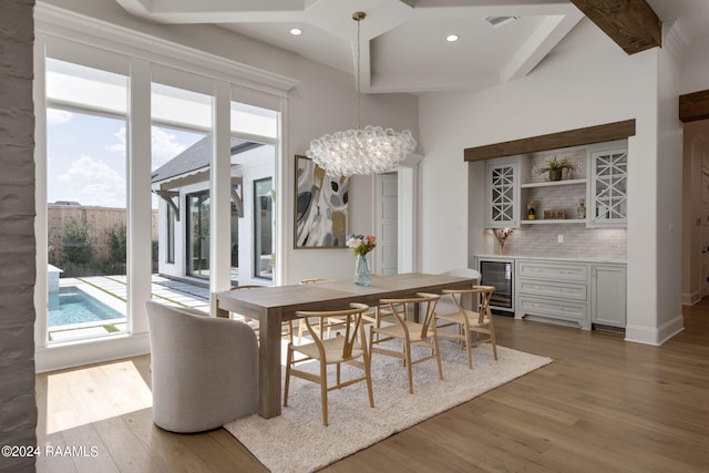 dining area featuring a notable chandelier, beverage cooler, bar area, and dark hardwood / wood-style flooring