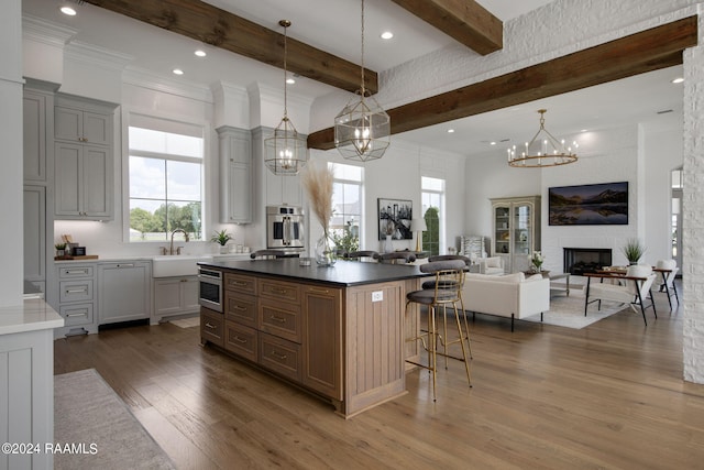 kitchen featuring a center island, dark wood-type flooring, beam ceiling, a fireplace, and stainless steel oven