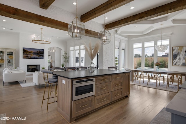 kitchen featuring a center island, hardwood / wood-style flooring, hanging light fixtures, a large fireplace, and stainless steel oven