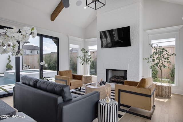 living room with light wood-type flooring, a fireplace, beam ceiling, and high vaulted ceiling