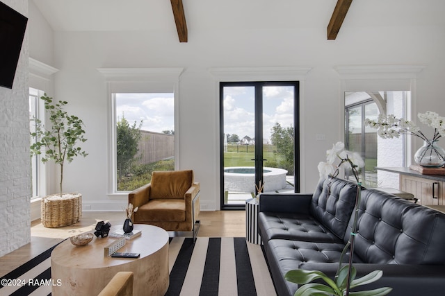 living room with a healthy amount of sunlight, light hardwood / wood-style floors, and beam ceiling