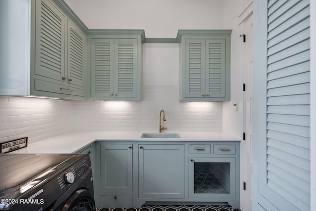 kitchen featuring decorative backsplash, washer / dryer, and sink