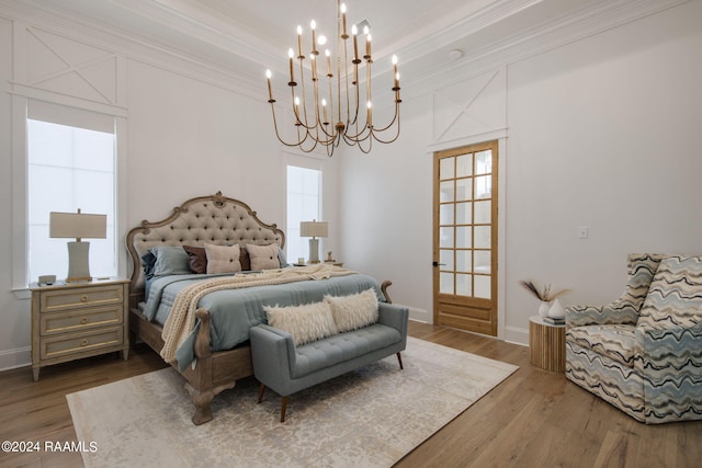 bedroom featuring wood-type flooring, an inviting chandelier, and ornamental molding