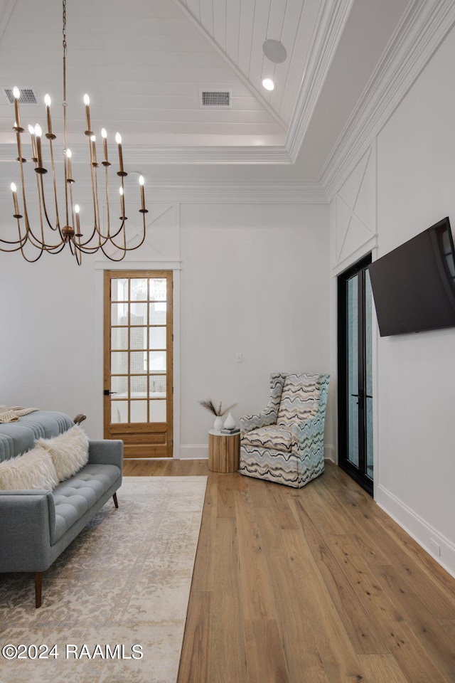 living area featuring ornamental molding, an inviting chandelier, high vaulted ceiling, and hardwood / wood-style flooring