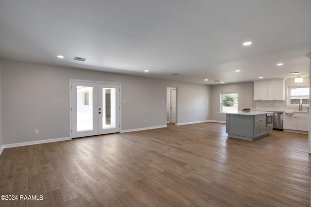 kitchen with a healthy amount of sunlight, white cabinets, a kitchen island, and hardwood / wood-style flooring