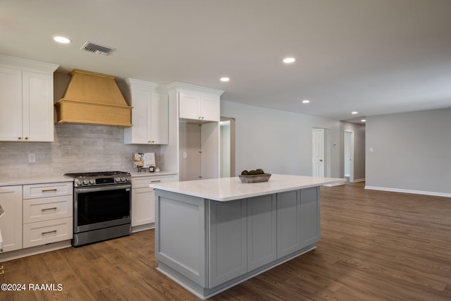 kitchen with custom range hood, white cabinetry, dark wood-type flooring, stainless steel gas range oven, and a center island