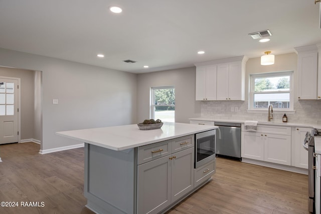 kitchen featuring appliances with stainless steel finishes, light wood-type flooring, a kitchen island, and a healthy amount of sunlight