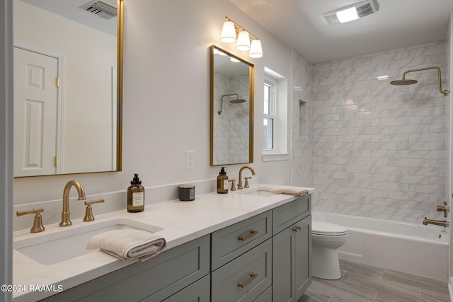 full bathroom with wood-type flooring, tiled shower / bath, vanity, and toilet