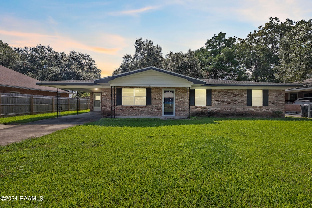 ranch-style house featuring a lawn and a carport