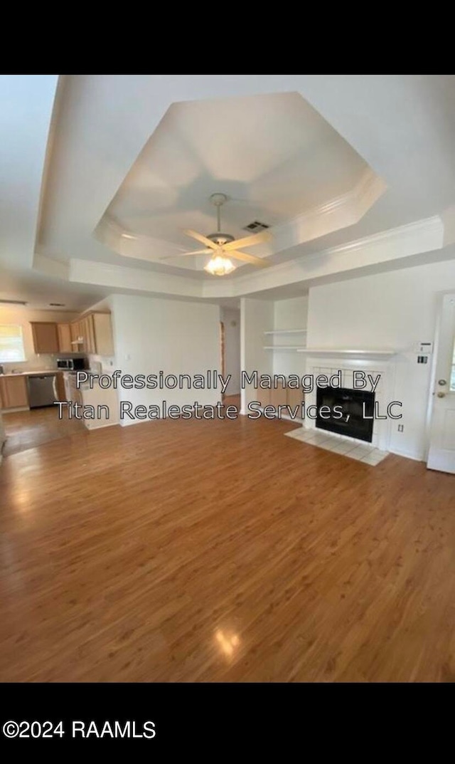 unfurnished living room with ceiling fan, a tray ceiling, and hardwood / wood-style floors