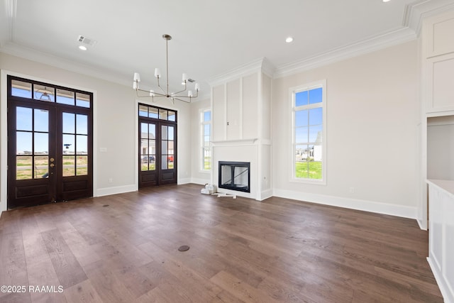 unfurnished living room featuring crown molding, french doors, dark wood-style flooring, plenty of natural light, and a chandelier