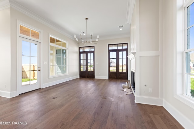 interior space with french doors, ornamental molding, baseboards, a chandelier, and dark wood finished floors
