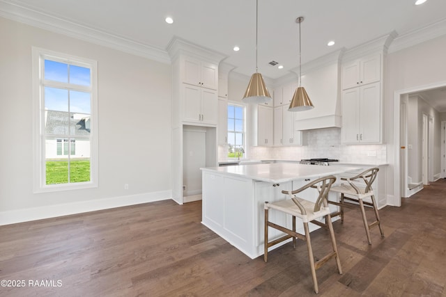 kitchen featuring light countertops, custom exhaust hood, ornamental molding, and white cabinets