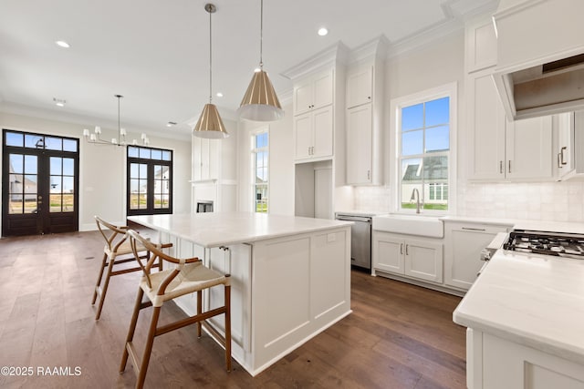 kitchen with french doors, ornamental molding, backsplash, a sink, and dishwasher