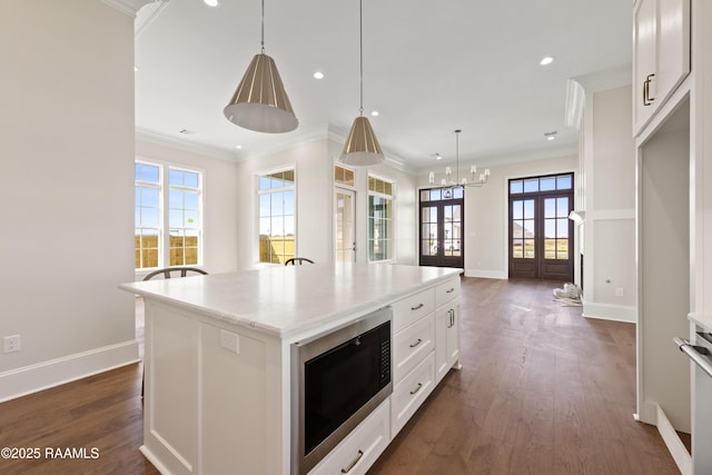 kitchen with crown molding, french doors, dark wood-style flooring, a kitchen island, and built in microwave