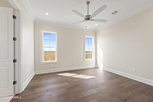 spare room with a ceiling fan, dark wood-type flooring, baseboards, visible vents, and ornamental molding