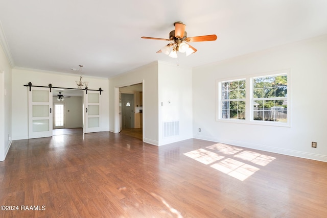 unfurnished living room featuring ceiling fan, ornamental molding, dark hardwood / wood-style floors, and a barn door