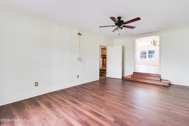 spare room with dark wood-type flooring, ceiling fan with notable chandelier, and crown molding