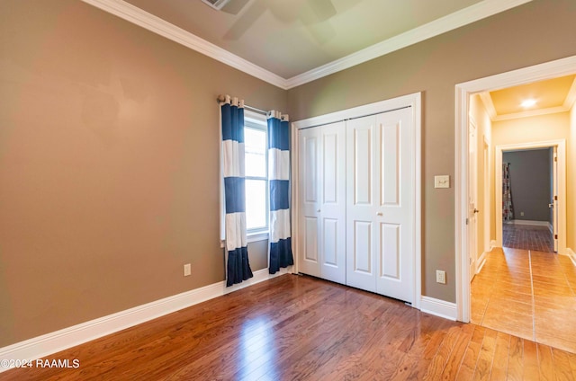 unfurnished bedroom with ceiling fan, hardwood / wood-style flooring, a closet, and ornamental molding