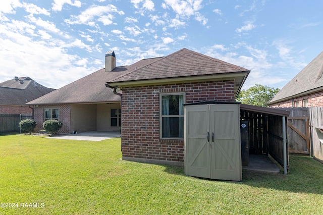 back of house featuring a lawn, a patio, and a shed