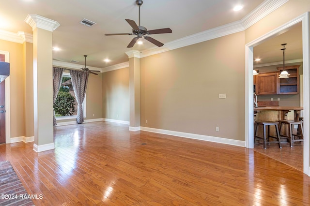 unfurnished living room featuring ornamental molding, decorative columns, hardwood / wood-style flooring, and ceiling fan