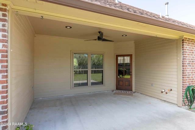 view of exterior entry with ceiling fan and a patio area