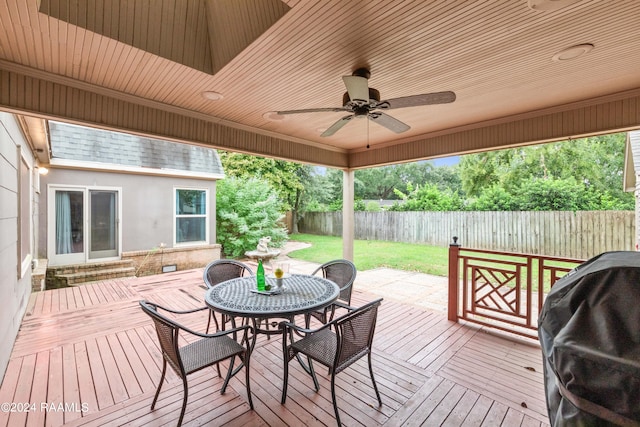 deck featuring ceiling fan, grilling area, and a lawn