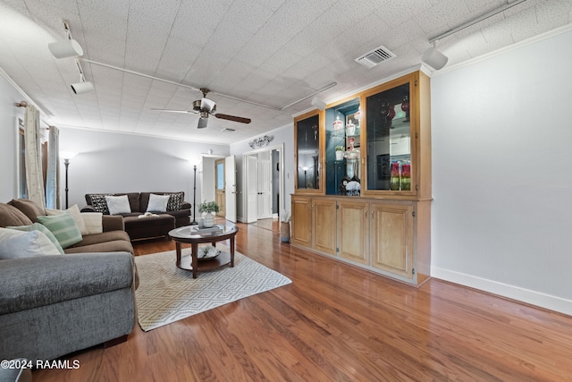 living room featuring ornamental molding, wood-type flooring, and ceiling fan