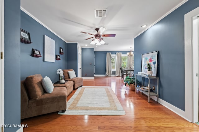 living room featuring crown molding, hardwood / wood-style flooring, and ceiling fan with notable chandelier