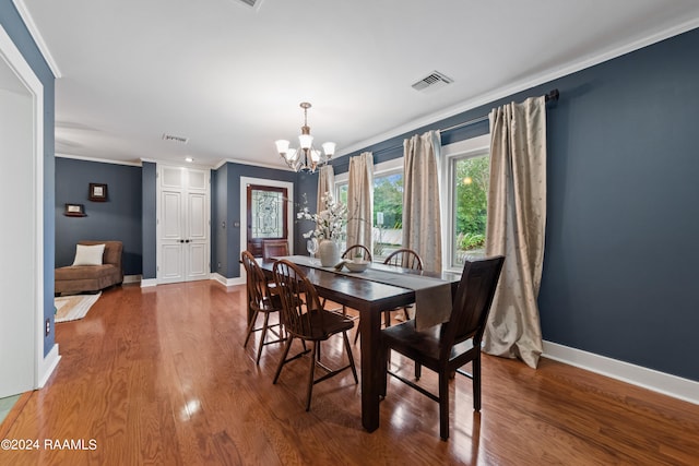 dining room featuring crown molding, wood-type flooring, and an inviting chandelier