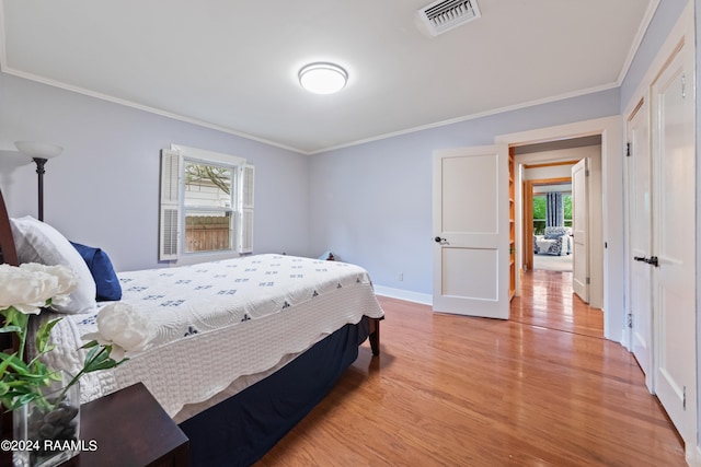 bedroom featuring light hardwood / wood-style floors, multiple windows, and ornamental molding