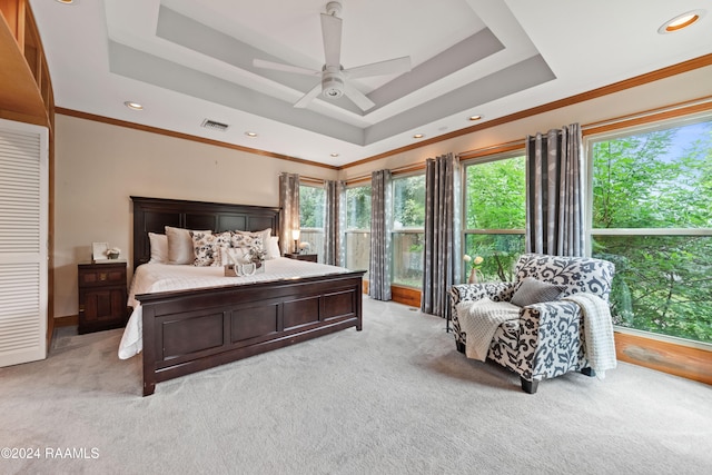 carpeted bedroom featuring ceiling fan, ornamental molding, and a tray ceiling