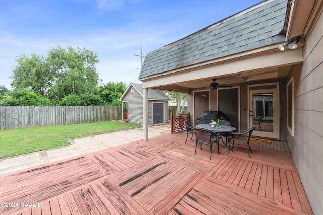 deck with a yard, a patio, grilling area, ceiling fan, and a storage shed