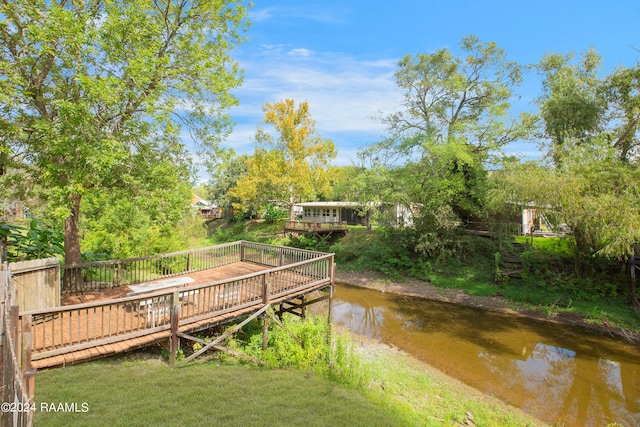 dock area with a yard and a deck with water view