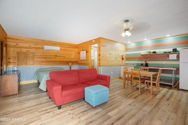 living room with light wood-type flooring, wood walls, an AC wall unit, and ceiling fan