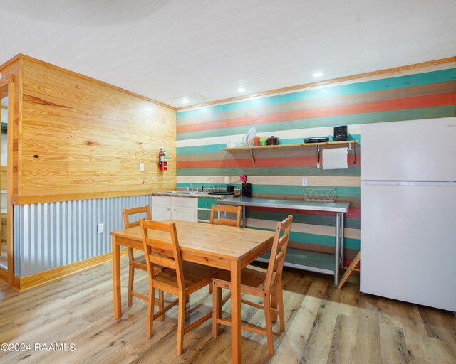 dining area featuring wood walls, sink, and light hardwood / wood-style flooring