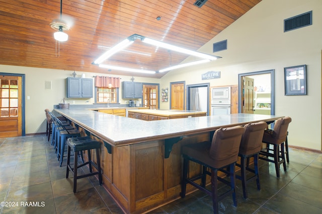 kitchen featuring a breakfast bar area, stainless steel fridge, sink, and wooden ceiling