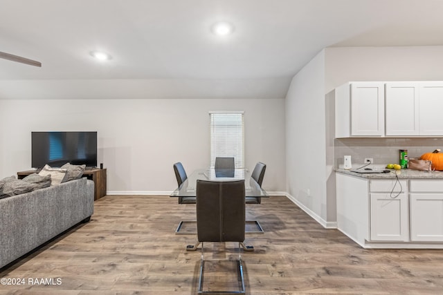 dining room with vaulted ceiling and light hardwood / wood-style flooring