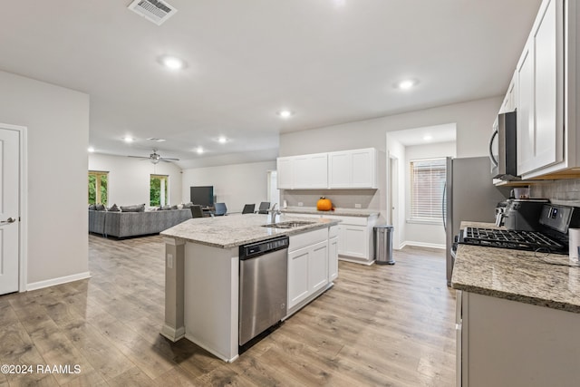 kitchen featuring light stone counters, a kitchen island with sink, white cabinetry, light wood-type flooring, and appliances with stainless steel finishes