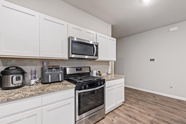 kitchen featuring light hardwood / wood-style flooring, white cabinets, decorative backsplash, and stainless steel appliances